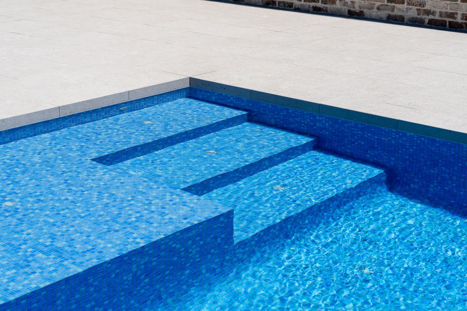 Close view of tiled steps and a bench inside a completed Enchanted concrete pool