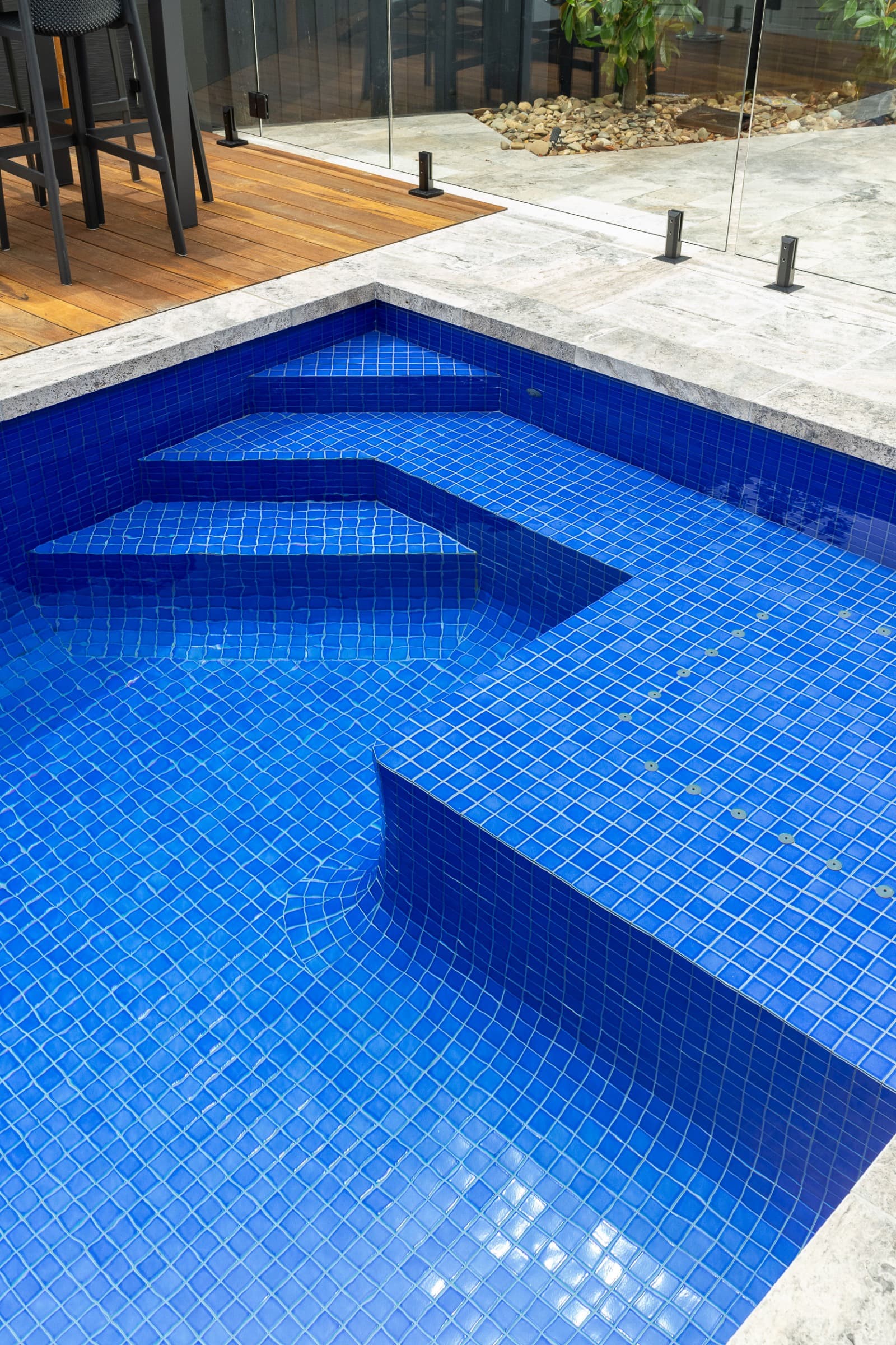 Detailed view of tiled steps and curved seating in a completed Enchanted concrete pool