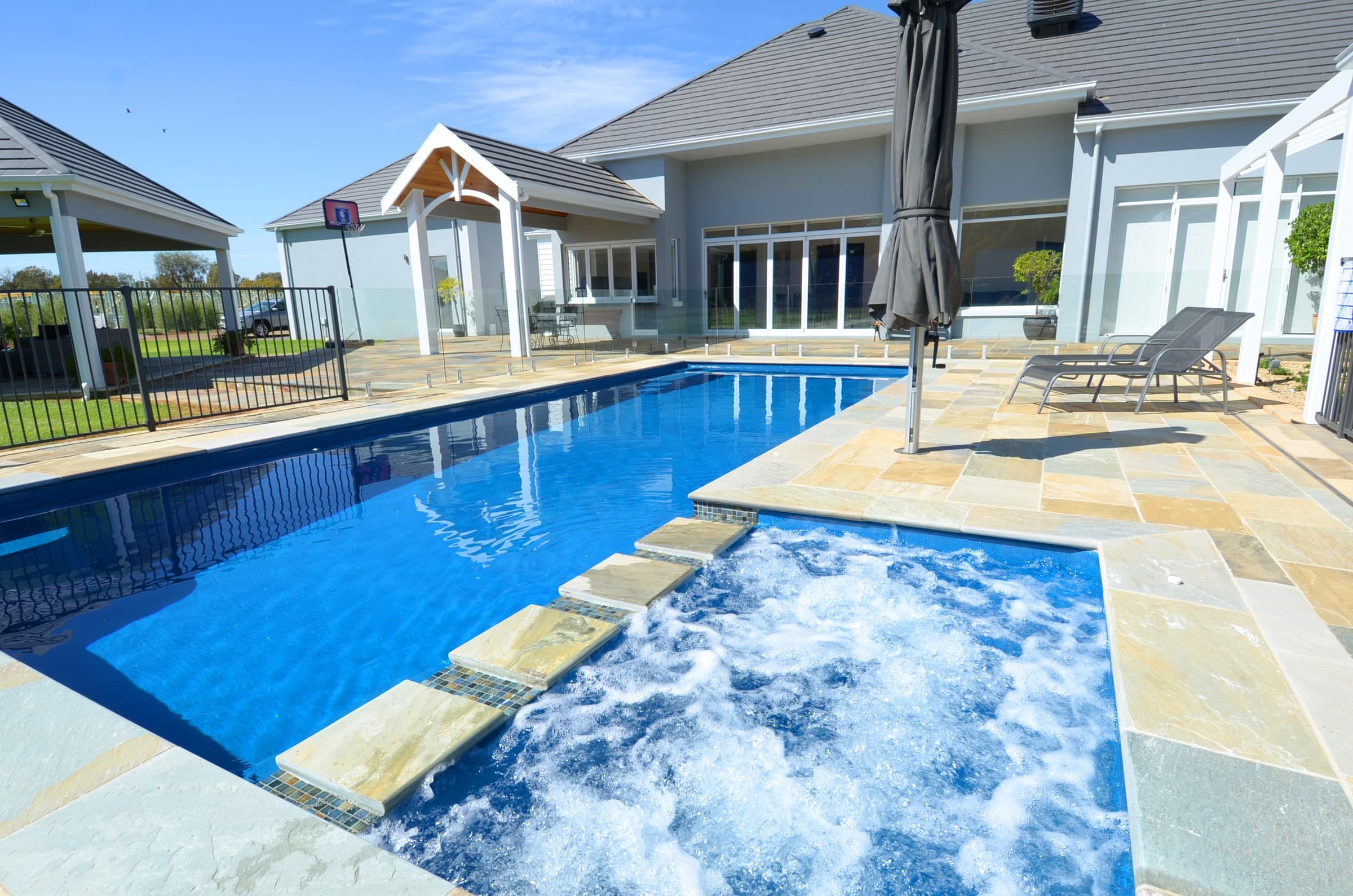 Integrated fibreglass spa beside a long swimming pool