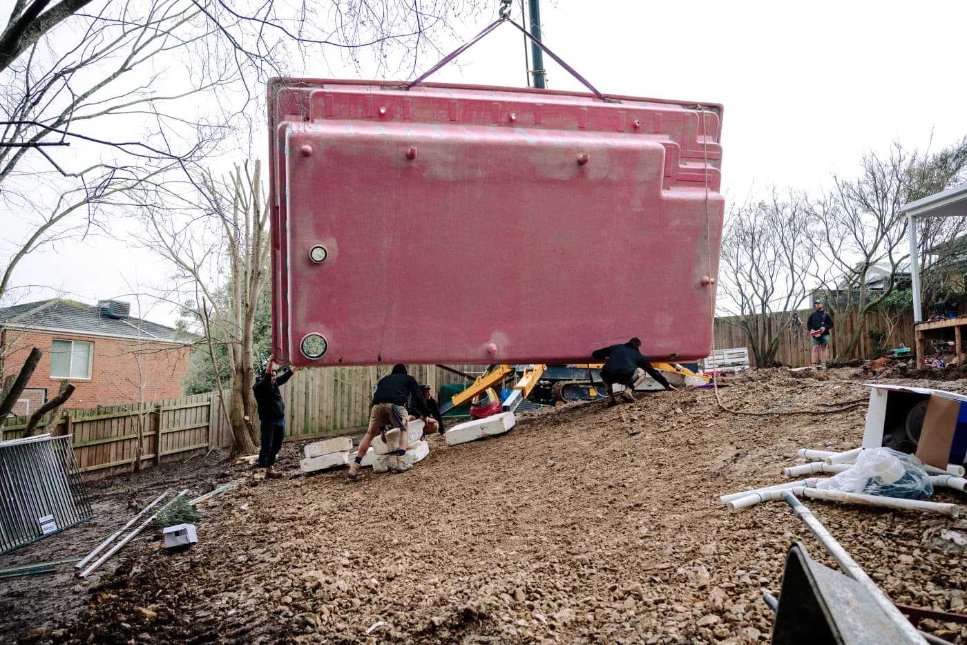 Enchanted Pools team guiding a fibreglass pool shell into position