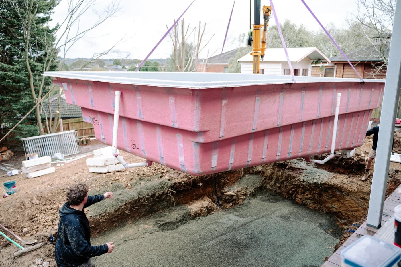 Enchanted Pools team lowering a fibreglass pool shell into an excavated site