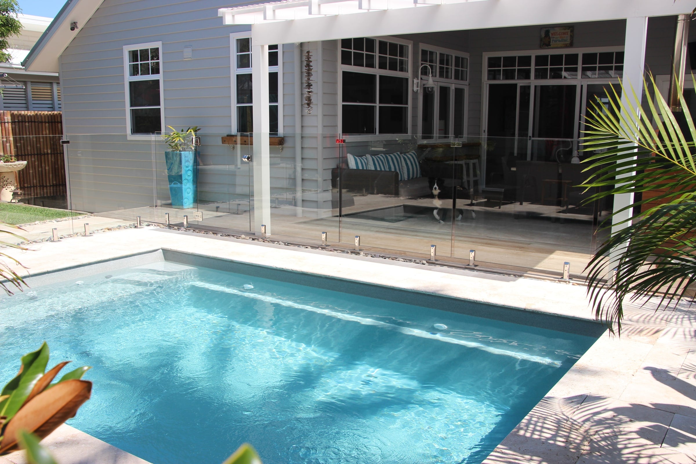 Plunge pool beside a bright weatherboard courtyard
