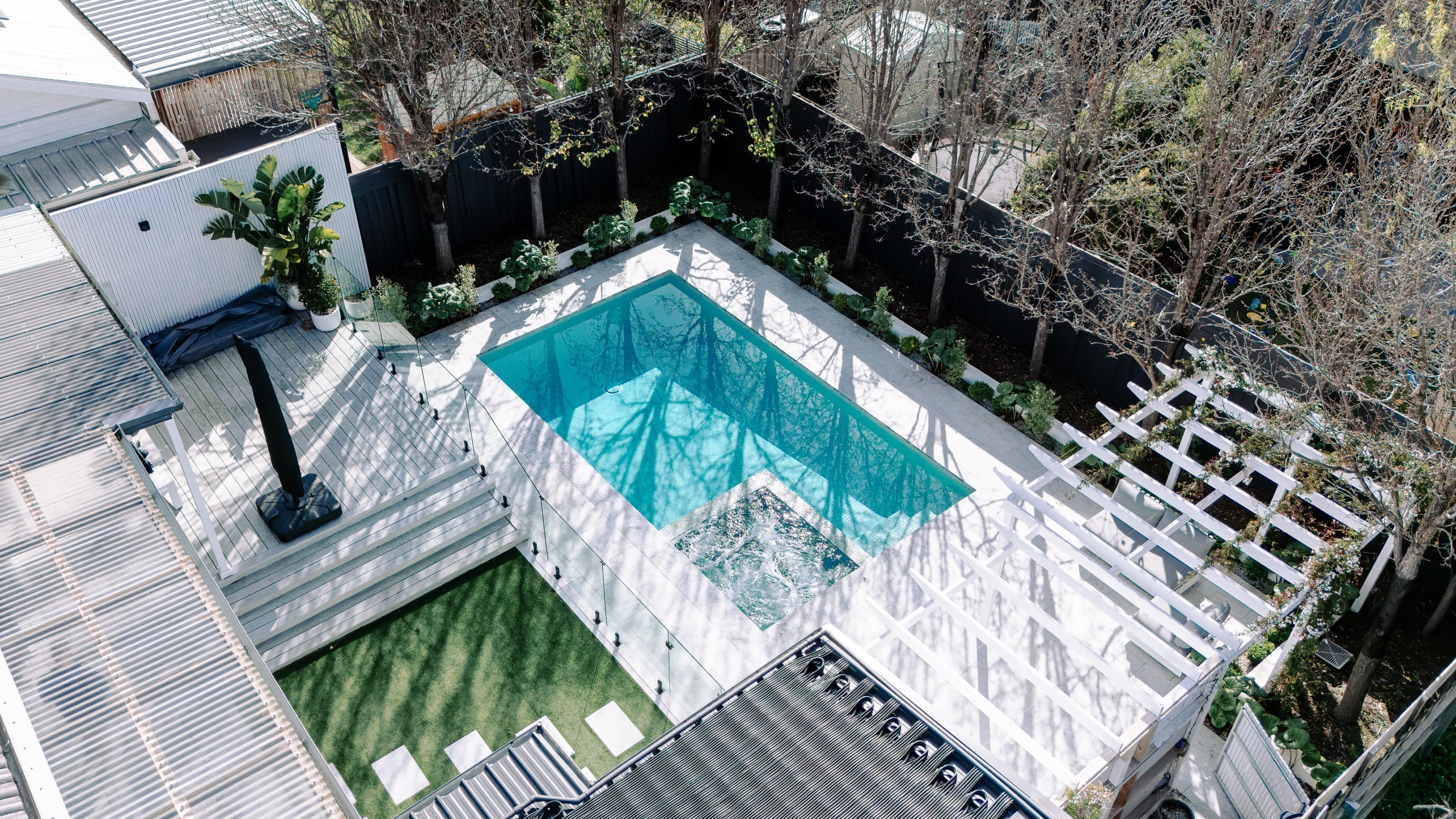 Aerial view of the Bentleigh concrete pool, integrated spa, white pergola and established garden