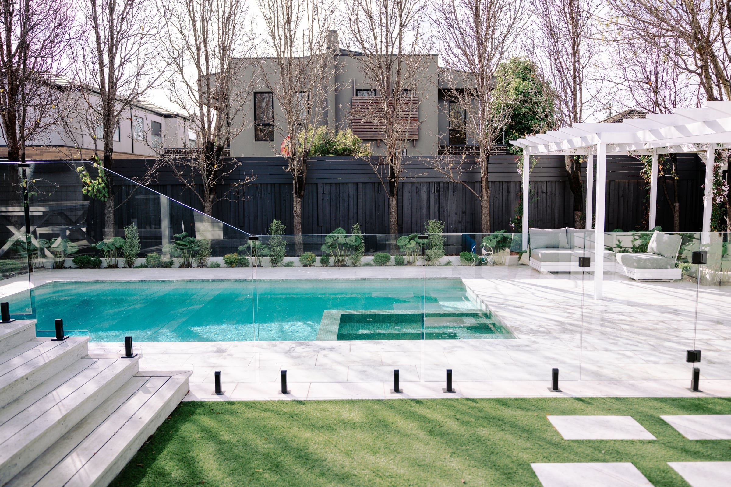 View from the home's deck across the glass fence to the pool and garden