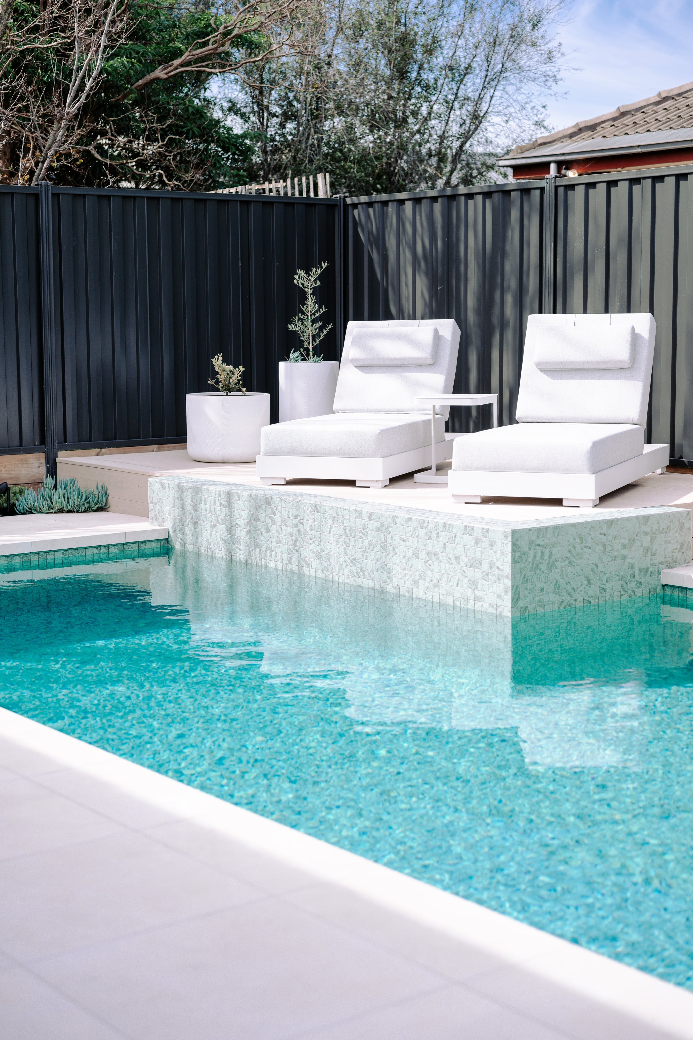 Portrait view across the ceramic mosaic pool towards the raised sun deck