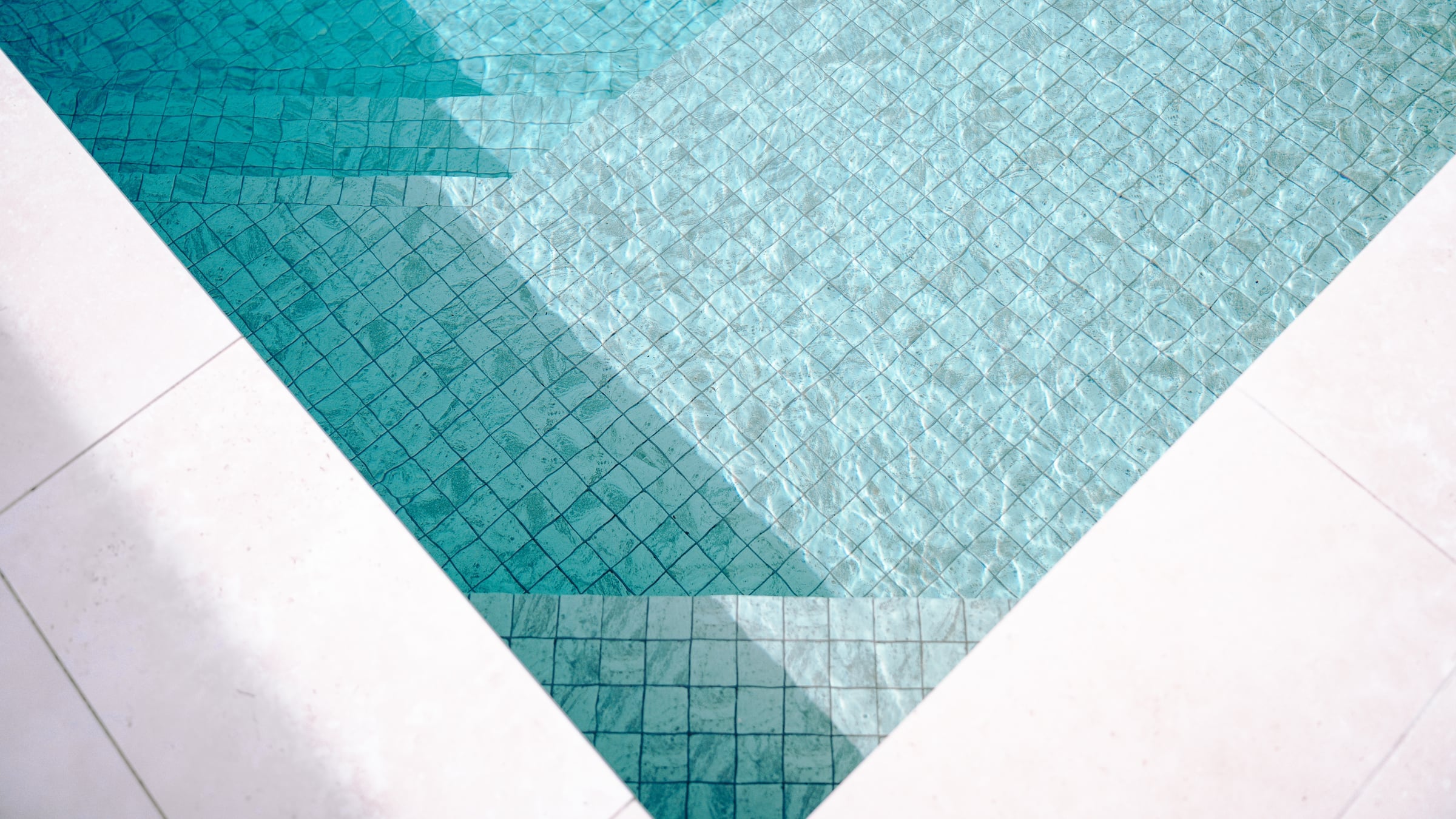 Ceramic mosaic entry steps and shallow seating beneath the pool water