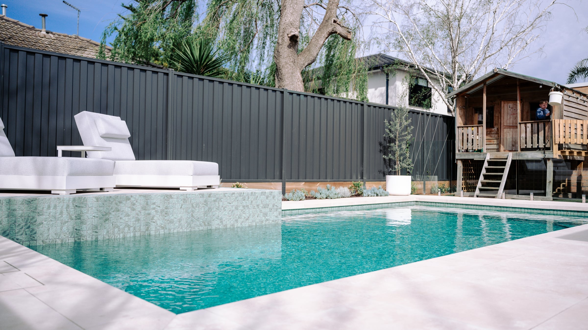 Water-level view of the raised mosaic wall and white sun lounges