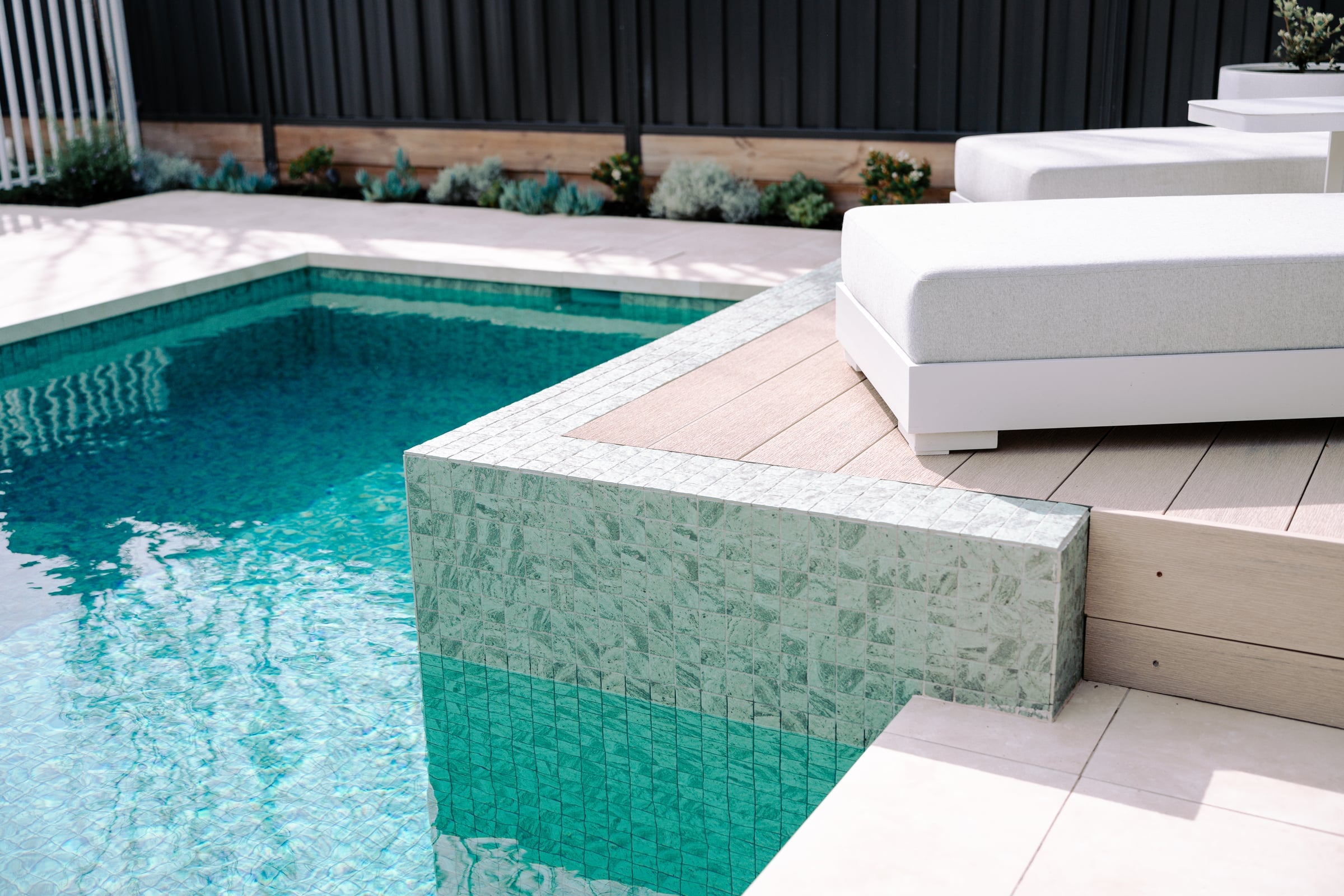 Timber deck meeting the raised ceramic mosaic pool wall