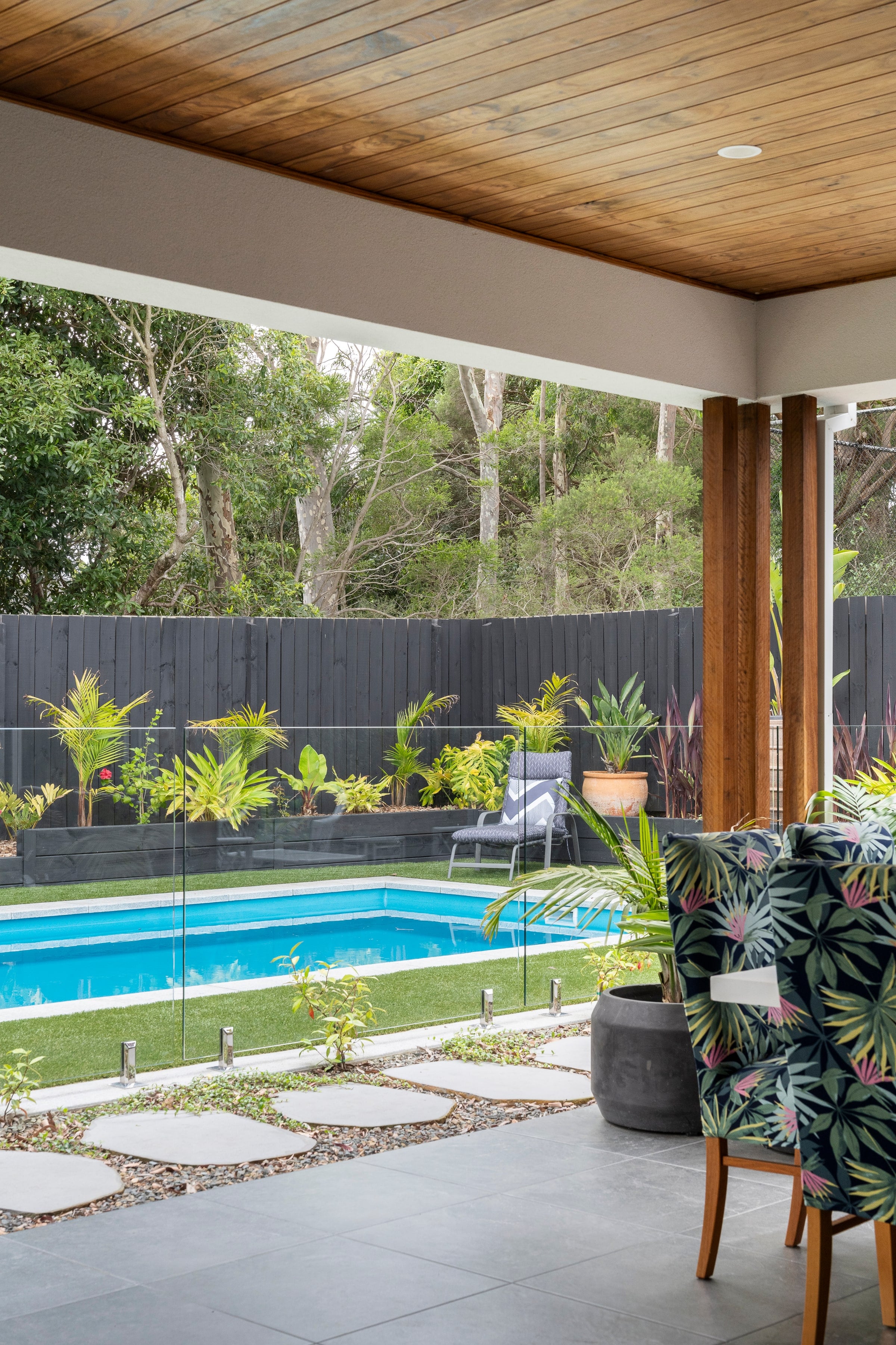 Glass-fenced pool edge beside tropical planting in Frankston South
