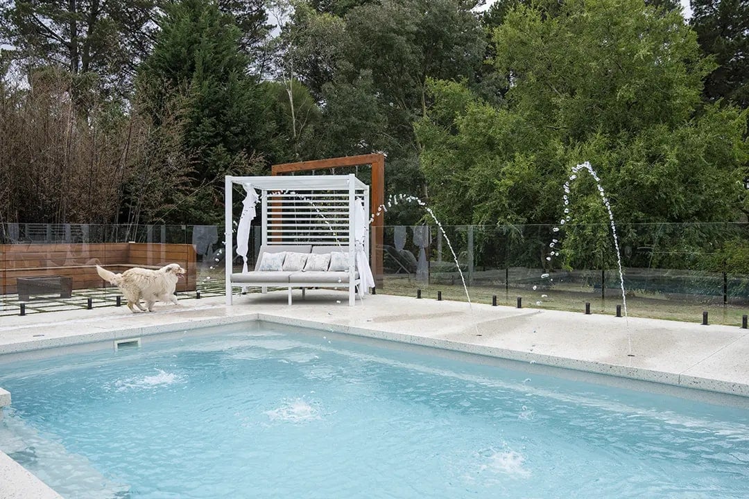 Fountain jets arcing into the pool beside a day bed in Pearcedale